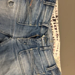 Ljusblå Diesel jeans - Säljer ett par ljusblå Diesel jeans med slitna detaljer och patchade hål. Jeansen är inte bootcut men inte helt raka ben, de är inte så långa som man tror de passar bra i längden på mig och jag ör runt 160 något de har klassiska fickor och coolt mönstrat innerfoder i midjan. Perfekt för dig som gillar en avslappnad och trendig look. Orginalt köpts för runt 2000 men nu säljer jag de för mer än hälften av priset!