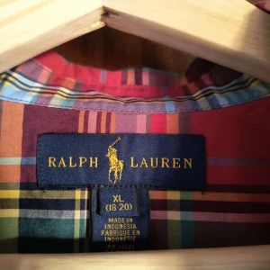 Rutig skjorta från Ralph Lauren XL - Fet rutig skjorta från Ralph Lauren i storlek XL. Skjortan har en klassisk krage, knäppning framtill och lång ärm. Färgerna är röd, blå, gul och grön i ett snyggt rutmönster. Perfekt för dig som vill sticka ut med stilren preppy-vibe.