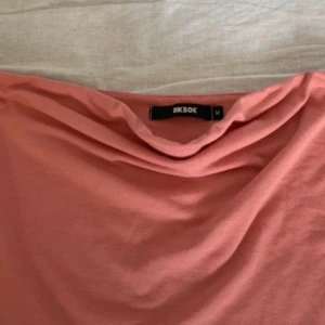 Tubtopp - Säljer en snygg rosa topp från BikBok i storlek M-S. Toppen har en draperad halsringning som ger en cool och trendig look. Tillverkad i mjukt material som känns skönt mot huden. Perfekt för dig som gillar stilrena plagg med en twist.