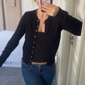 Svart kofta med guldknappar - Svart kofta med snygga guldknappar framtill. Klassisk rund halsringning och långärmad modell. Perfekt att slänga över ett linne eller topp för en clean och stilren look.