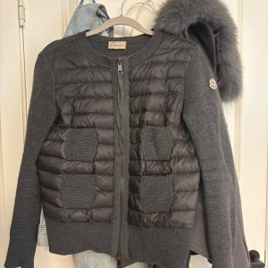 Grå quiltad kofta från Moncler - Säljer härmed min ur snygga Moncler cardigan med quiltad front och stickade ärmar. Två stickade fickor framtill och dragkedja hela vägen. Klassisk Moncler-logga på ärmen. Perfekt för lager-på-lager under höst och vinter. ÄKTA 