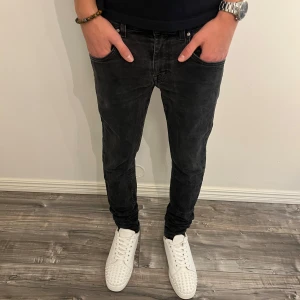 Svarta slim jeans Tiger of Sweden - Svarta jeans från Tiger of Sweden i slim fit-modell. Jeansen har en snygg tvättad look, klassiska bakfickor och detaljer i svart. Tillverkade i ett mjukt och stretchigt jeanstyg för en bekväm passform.