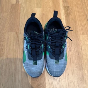 Grå och gröna sneakers från Puma - Säljer ett par snygga sneakers från Puma i grått och grönt med svart mesh och coola rutmönster på ovandelen. Skorna har snörning och en sportig vibe, perfekta för dig som gillar streetstyle. Sulan är vit med svarta detaljer och de har en bekväm passform.