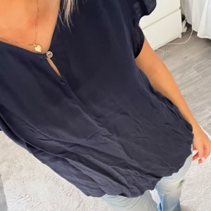Mörkblå blus från Hilfiger Denim XS - Säljer en mörkblå blus från Hilfiger Denim i storlek XS. Blusen har korta ärmar, v-ringning med knappdetalj och är tillverkad i ett mjukt, tunt material som känns skönt mot huden. Perfekt till jeans eller kjol för en enkel och snygg look. Tveka inte att höra av dig!💗