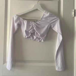 Vit croppad topp från Madlady XS - Använd 1 gång, nyskick. En Axel är off shoulder och den andra är som vanligt. Tröjan är scrunched i mitten. Tröjan är väldigt stretchig.  Vänligen läs min bio innan du gör ett köp; där hittar du bland annat information om leveransprocessen med mera 😊