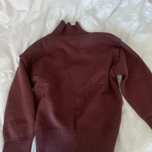 Mörk/brun  polotröja i stickad bomull - Säljer en mörkbrun polotröja med ribbad hög krage och breda ribbade muddar. Tröjan är oanvänd, (nypris) 450kr (mitt pris) 350. Det går att buda, så gör gärna det🫰🏼