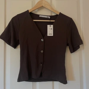 Topp med knappar - Topp med silvriga knappar från Lager157. Aldrig använd med lappen kvar.