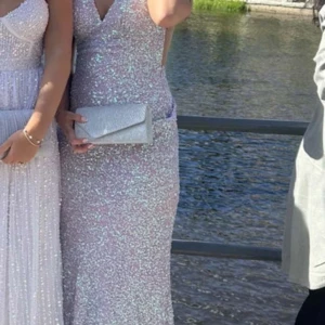 Dressroom Linné klänning - Säljer min fina balklänning från dressroom Linné. Köpt begagnad så har tyvärr inget kvitto. Eftersom det är paljetter så skiftar den i i färg beroende på vilket ljus det är som man kan se på bilderna. Banden är reglerbara så passar allt mellan xs-m skulle jag säga, men enligt lappen är den en xs. Bra skick. Eftersom den har lite släp så är den lite smutsig nedtill på insidan men inget som syns eller stör funktionen.