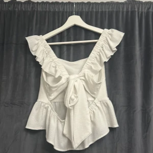 Vit volangtopp med knyt i ryggen - Supersöt vit topp med volangdetaljer och rosett i ryggen🎀🎀🎀🎀