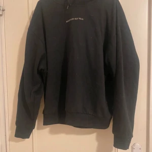 Svart hoodie med peace-tryck - Svart hoodie med texten 'MAKE ART NOT WAR' framtill och stort vitt peace-märke på ryggen. Oversized passform, mjuk och skön med huva och långa ärmar. Perfekt för dig som gillar streetstyle och statement-plagg.