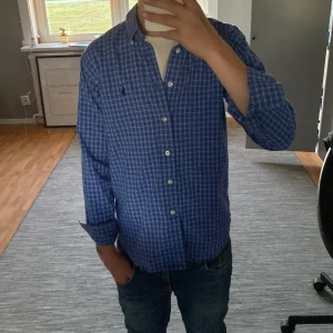 Blårutig skjorta från Ralph Lauren - Snygg blårutig skjorta från Ralph Lauren, nästan helt ny. Använd fåtal gånger, inga skador på skjortan. Ba o höra av er vid frågor 😃
