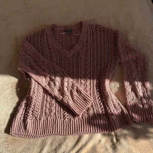 Rosa stickad tröja med v-ringning Primark - Säljer en rosa stickad tröja från Primark med v-ringad hals och långärmad design. Tröjan har ett snyggt hålmönster och breda ribbade muddar vid ärmslut och nederkant. Perfekt för lager-på-lager och chill vibes.