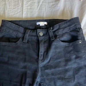 Svarta jeansbyxor från Gina Tricot - Svarta jeansbyxor från Gina Tricot med klassisk femficksdesign och snygga detaljer på bakfickan. Byxorna har ”medel” midja och en bootcut modell. Materialet är jeans. 