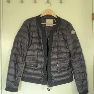 Tunn Moncler dunjacka - Har tecken på användning och små slitningar på dragkedjan. Storlek 2/m.