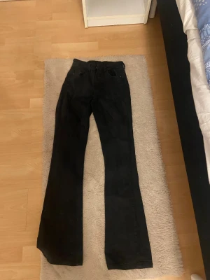 Svarta bootcut jeans - Säljer ett par svarta jeans med bootcut passform. Byxorna har klassisk femficksdesign och är tillverkade i jeansmaterial. Perfekta för dig som gillar en lite vidare siluett nedtill och vill ha en cool look.