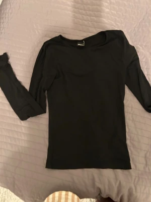 Svart långärmad tröja Gina Tricot - En stilren svart långärmad tröja från Gina Tricot i storlek S. Tröjan har en klassisk rund halsringning och är gjord i mjuk bomull, perfekt för lager-på-lager eller som basplagg. 