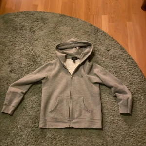 Grå hoodie från Polo Ralph Lauren - Jag säljer en grå hoodie från Ralph Lauren, mycket bra skick närmare nytt skick och med qr kod, för ett lågt pris. Pris kan vidare diskuteras.