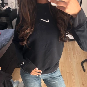  Nike sweatshirt - Svart sweatshirt från Nike med vit broderad swoosh på bröstet och ärmslutet. Tröjan har rund hals, lång ärm och en normal passform. Lite mer använd än andra plagg men fortfarande i bra skick! Storlek S men passar också xs 