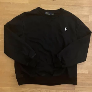 Svart Ralph Lauren tröja - Svart tröja från Polo Ralph Lauren med klassisk rund hals och långärmad design. Storlek L men passar bättre som storlek M 