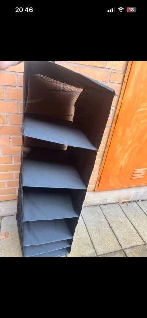 Hängande tygförvaring med 6 fack - Praktisk hängande tygförvaring med sex rymliga fack, perfekt för garderoben eller hallen. Svart tygmaterial, lätt att montera och flytta. I gott skick utan synligt slitage eller defekter. Idealisk för att organisera kläder, skor eller accessoarer.