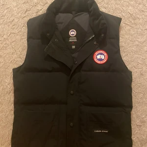 Svart väst från Canada Goose - Svart väst från Canada goose, har haft västen i 2 år men har använt den fåtal gånger. Den är i fint skick och inga märkbara problem med västen. OBS INGA RETURER…