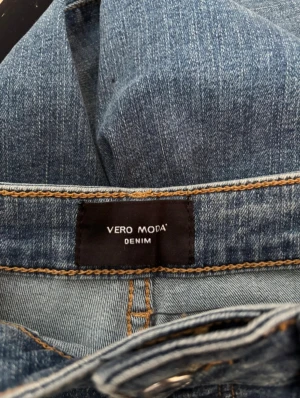 Blå jeans från Vero Moda - Snygga blå jeans från Vero Moda med klassisk femficksdesign och brunt läderpatch bak i midjan. Jeansen har rak passform och normal midja. Perfekta för en chill och stilren look.