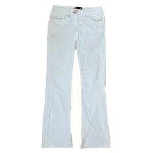 Vita bootcut jeans från Dolce & Gabbana - Snygga vita jeans från Dolce & Gabbana med bootcut passform. Byxorna har silverfärgade nitar och rosa stenar vid fickorna samt färgglada dekorationer på bakfickan. Tillverkade i Italien i mjuk bomull. Perfekt för dig som gillar detaljer och exklusiv stil. Jag skulle påstå att det är en lite mindre storlek så istället för 40 skulle jag säga att de är en 38🤍🐚 