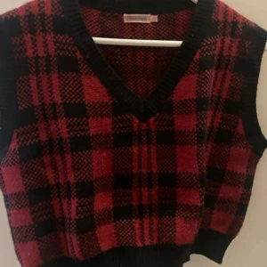 Rutig röd och svart stickad väst - Liten i storleken