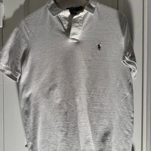 Vit pikétröja från Polo Ralph Lauren - Klassisk vit pikétröja från Polo Ralph Lauren i bomull med broderad logga på bröstet. Tröjan har korta ärmar, krage och knäppning med två knappar. Perfekt för en clean och stilren look.      Ny struken och ny tvättat 
