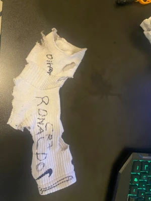 Vit ribbad DIY väst med CR7-tryck - Unik signerad strumpa i vit ribbad bomull från Nike, med autograferade texter som CR7 Ronaldo Yanne!och Dih från Ronaldo himself. Strumpan har flera hål som visar hur Ronaldo har kämpat igenom matcherna med dem. Perfekt för dig som gillar fotboll och autografer från fotbolls spelare som Kristian ronald mcdonald. IGEN NU GRABBAR KOM IGEN NU DÅ!!!!! OOOO YANNE YANNE SÖDERSTADION KOKAAARRRRRE 🏟️ 