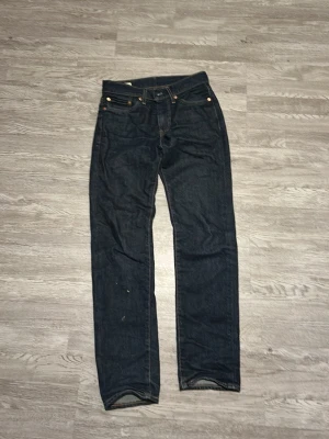 Levi's 511 mörkblå jeans W28 L30 - Snygga Levi's 511 jeans i mörkblå tvätt med klassisk femficksdesign och kontrastsömmar. Modellen är slim och har en rak passform som sitter schysst på benen. Jeansen är tillverkade i slitstarkt bomullsmaterial och har läderpatch bak i midjan.
