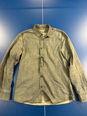 Grå jeans skjorta från J.Lindeberg slim fit - Snygg lite vintage jeans skjorta från J. Lindeberg. Skjortan är grå och storleken är Small. Skick 7/10 eftersom skjortan är lite äldre så kan det finnas lite missfärgning och tecken på användning men annars helt fel fri. Kom dm för fler frågor osv!