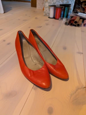 Röda italienska pumps i skinn, 38.5 - Snygga röda pumps från Vero Cuoio, tillverkade i Italien. Skorna har en spetsig tå och låg klack, vilket ger en klassisk och stilren look. Utsidan är i mjukt skinn och insidan är ljusgrå. Perfekt för dig som gillar färgstarka accessoarer.
