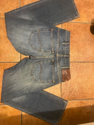 Lee Knox blå jeans W30 L32 - Snygga blå jeans från Lee i modellen Knox. Klassisk femficksdesign, raka ben och normal passform. Jeansen har en cool tvätt med lätt slitning och Lee-läderpatch bak i midjan. Perfekta för dig som gillar en tidlös och avslappnad look.Helt nya.