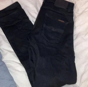 Svarta jeans från Nudie Jeans, 29/32 - Kolsvarta jeans från Nudie. Passformen är slim och modellen heter Grim Tim. Köpt på Kennedies för 1400kr. Använt någon enstaka gång men dem blev för tighta så säljer dem för halva priset.