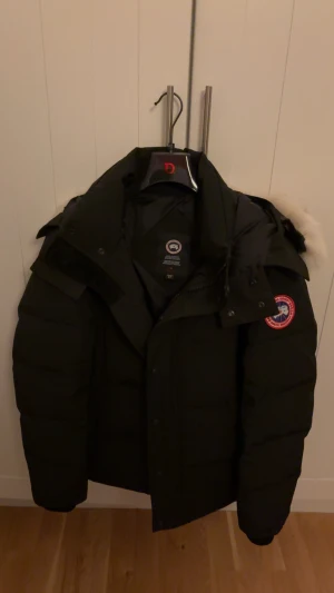 Canada Goose Wyndham - Canada Goose Wyndham med klassisk patch på armen. Perfekt för kalla vinterdagar och har en riktigt snygg, clean look.                                     Använd 1 vinter!