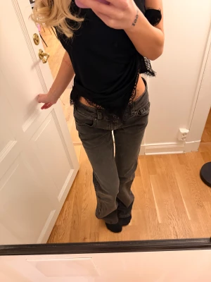 Gråa lågmidjade jeans från Gina  - Säljer ett par gråa jeans från Gina med låg midja och bootcut. Jeansen har klassiska fickor fram och bak, samt knappdetalj på bakfickorna. Materialet är slitstarkt denim och passformen är bootcut men lite stora för mig. 