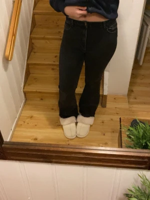 Svarta bootcut jeans - Snygga svarta jeans med bootcut passform och klassisk femficksdesign. Jeansen har en hög midja och är tillverkade i ett stretchigt denim-material som sitter bekvämt och framhäver siluetten. Perfekta för dig som gillar en tidlös look med lite extra edge.