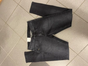 Svarta tighta jeans W28 L32 - Snygga svarta jeans med tight passform och smal fot. Klassisk femficksmodell i stretchigt jeanstyg som sitter riktigt schysst. Perfekta för dig som gillar en smal siluett och vill ha ett par stilrena jeans till garderoben.
