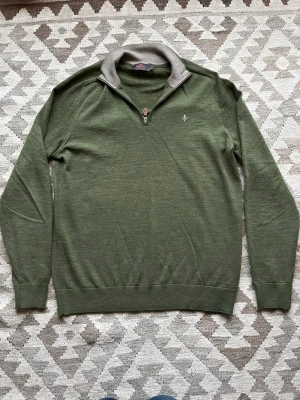 Olivgrön half zip stickad tröja - Säljer en olivgrön merinoullströja med half/quarter zip och medel hög krage. Tröjan har lång ärm och en clean, stilren look som passar perfekt till både jeans och chinos. Materialet är mjukt och andas, vilket gör den skön att bära hela dagen. Endast använd två gånger, inga defekter. Säljs då den var för liten. :)