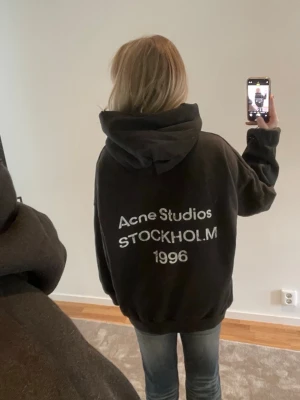 Acne studios logo hoodie - Supersnygg hoodie från acne med deras logga på ryggen. Knappt använd. Storlek: M, men väldigt oversized. Hoodiens modell har en ”urtvättad” svart färg dock slitagedetaljer❤️