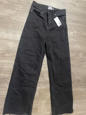 Svarta wide jeans från 157, XS - Svarta jeans från 157 i modellen Jeans Lane. De har hög midja, raka ben med wide fit och råa kanter nertill. Klassisk femficksdesign och tillverkade i bomull. Perfekta för dig som gillar en avslappnad och trendig look. Nyskick, aldrig använda