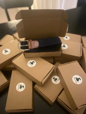 Marinblått bälte med bruna detaljer - Snyggt marinblått bälte från Viptunneln med silverfärgat spänne och bruna skinn-detaljer vid spännet. Perfekt accessoar för att lyfta din outfit och funkar till både jeans och chinos.