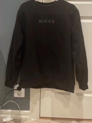 Svart sweatshirt från NICCE - Svart sweatshirt från NICCE med rund halsringning och diskret logotyp framtill. Tröjan har en klassisk passform med långa ärmar. Perfekt för en schysst och avslappnad look.