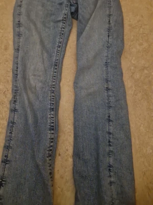 Blå bootcut jeans från Gina Tricot - Säljer ett par klassiska blå bootcut jeans från Gina Tricot. Jeansen har en lätt utsvängd passform och är tillverkade i denim med snygga söm-detaljer längs benen. Perfekta för dig som gillar en tidlös och avslappnad stil. Nypris-350kr