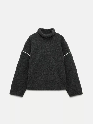 Mörkgrå stickad polotröja - Mörkgrå stickad polotröja med vita detaljer vid ärmarna. Tröjan har en avslappnad passform, långa ärmar och hög krage. Perfekt för lager-på-lager och en stilren look.