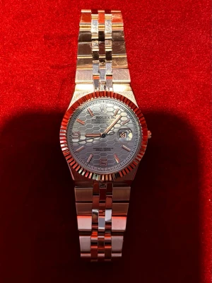 Rolle klocka Landweller - Snygg Rolle klocka i färgen silver. Urtavlan har ett unikt hexagonmönster i ljusblått färg, samt datumvisning. Klassisk räfflad bezel och robust metallarmband ger en lyxig känsla.