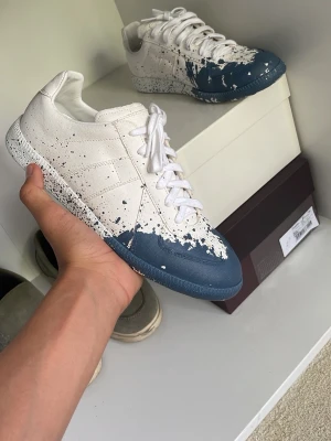 Maison margiela - Säljer ett par unika sneakers i vitt med blå färgstänk och mönstrad sula. Allt og medföljer STORLEK 40,5 MEN SITTER SOM 41 OM DU TAR UT SULAN!
