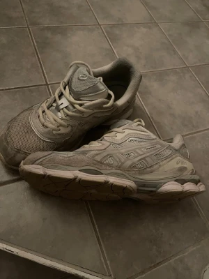 Beige ASICS sneakers med meshdetaljer - Säljer ett par beige ASICS sneakers med klassisk siluett och meshpaneler för extra ventilation. Skorna har snörning och diskreta loggor på sidorna. Snygg chunky sula och neutrala färgtoner som passar till det mesta.