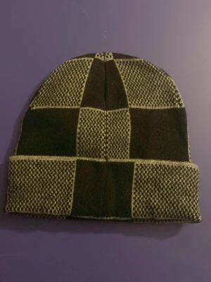 Zara rutmönstrad mössa - Säljer en snygg svart och grå mössa från zara med rutmönster och uppvikt kant. Perfekt accessoar för dig som gillar exklusiv streetwear.